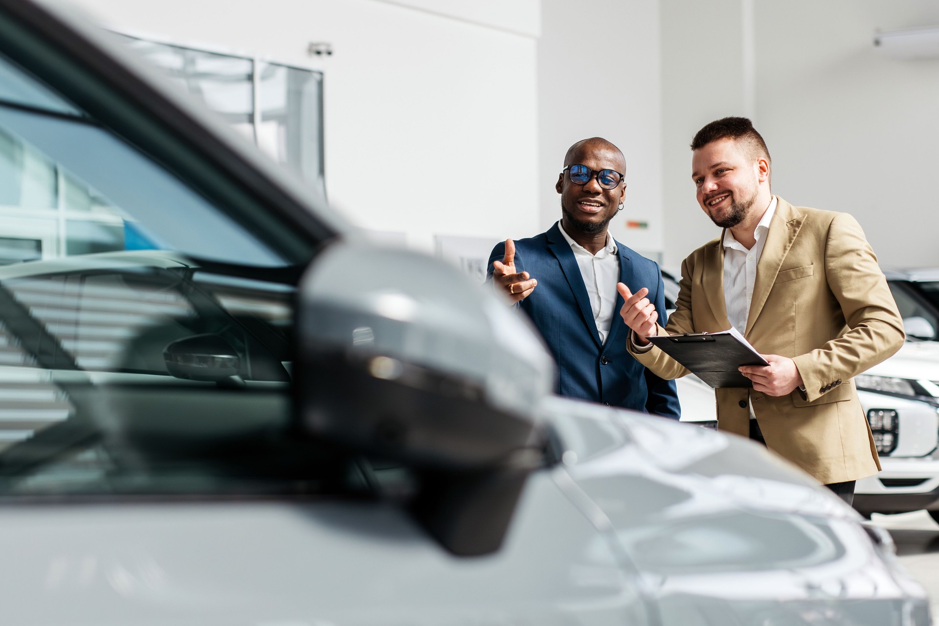 An auto dealer consults and signs an agreement to lease or buy a new car with a black businessman at a car dealership.